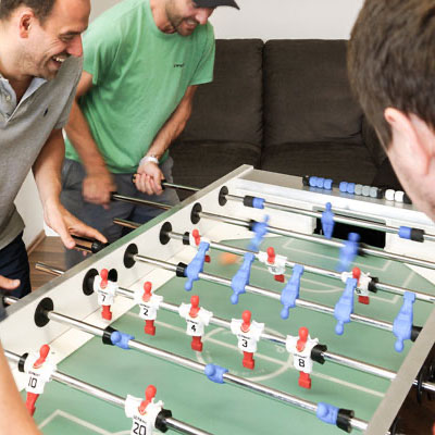 Mehrere Mitarbeiter spielen gemeinsam Tischkicker